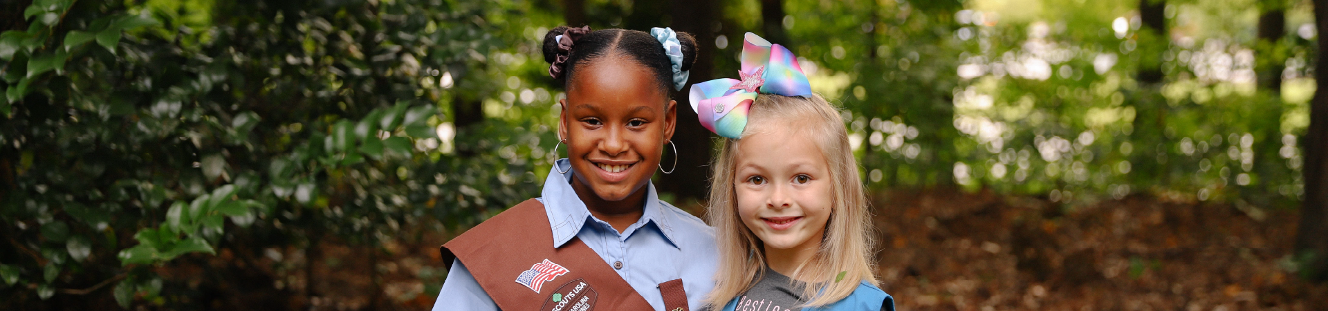  two girl scouts wearing uniforms smile 