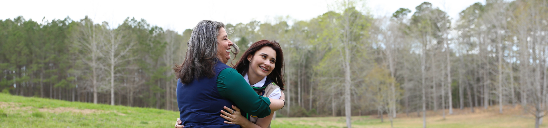  co-leader mom jokes around with Girl Scout daughter outdoors 