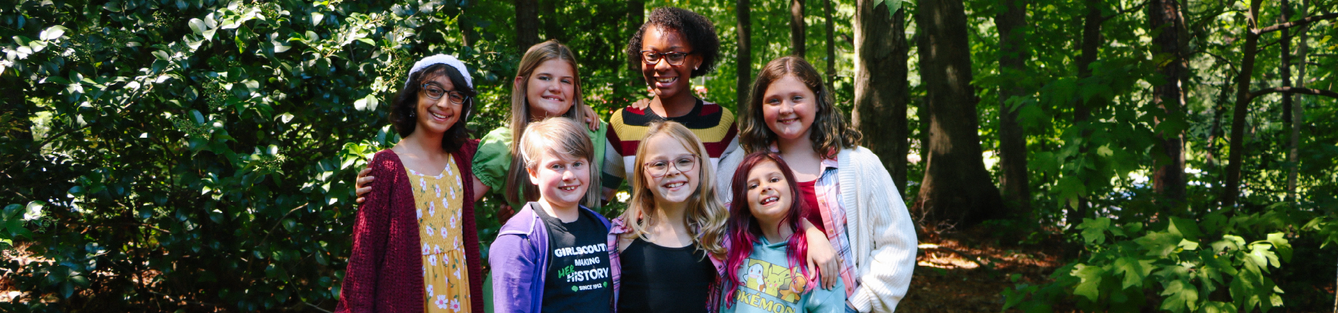  A group of Girl Scouts smile near the forest 