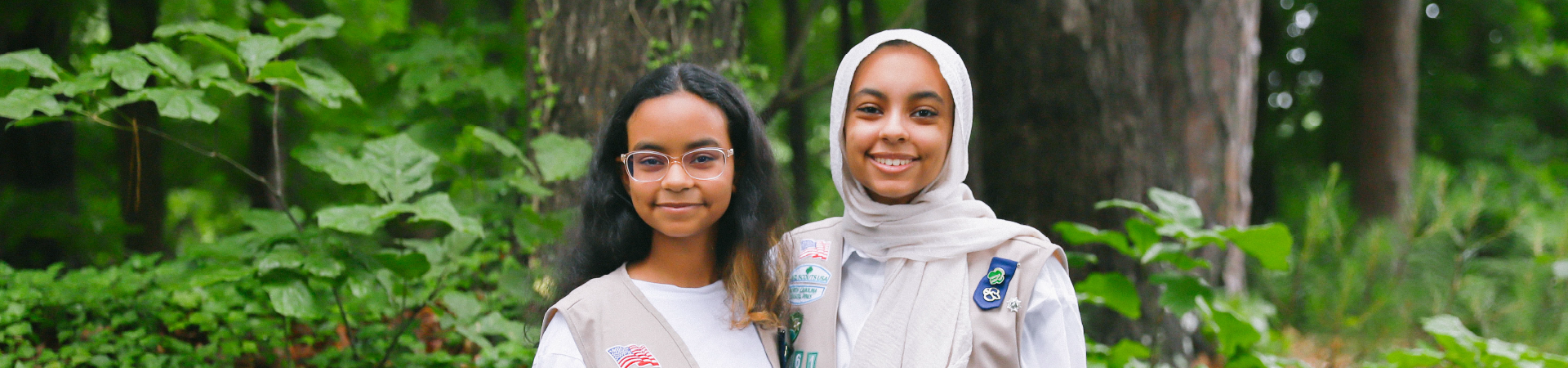  group of two older girl scouts smiling near foliage 