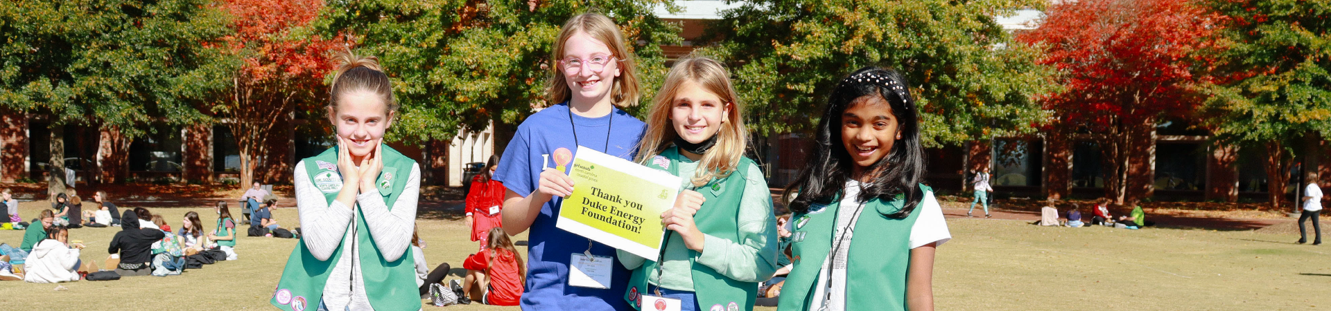  Two girls in forest hold "thank you for your support" sign 