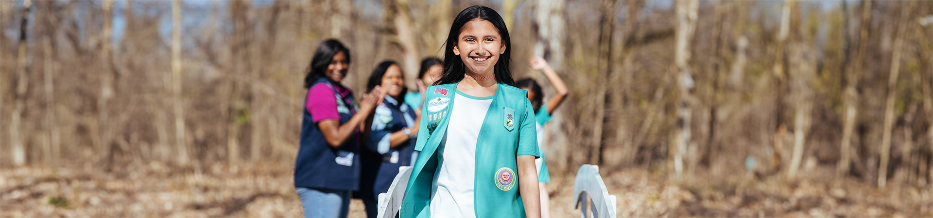  girl scout staff or volunteer wearing adult vest in woods smiling 