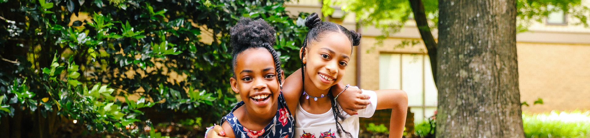  Two girls pose next to a tree and smile 