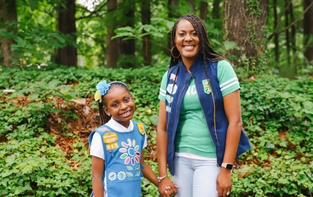 Girl Scout and her mother hold hands and smile