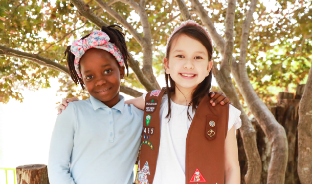 Daisy Girl Scout smiles in front of flower bed