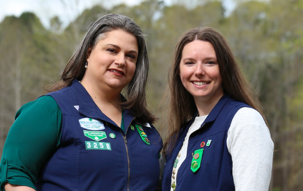 adult woman girl scout volunteer wearing vest outdoors smiling hiking