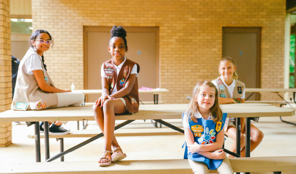 group of Girl Scouts sit on picnic table and bench