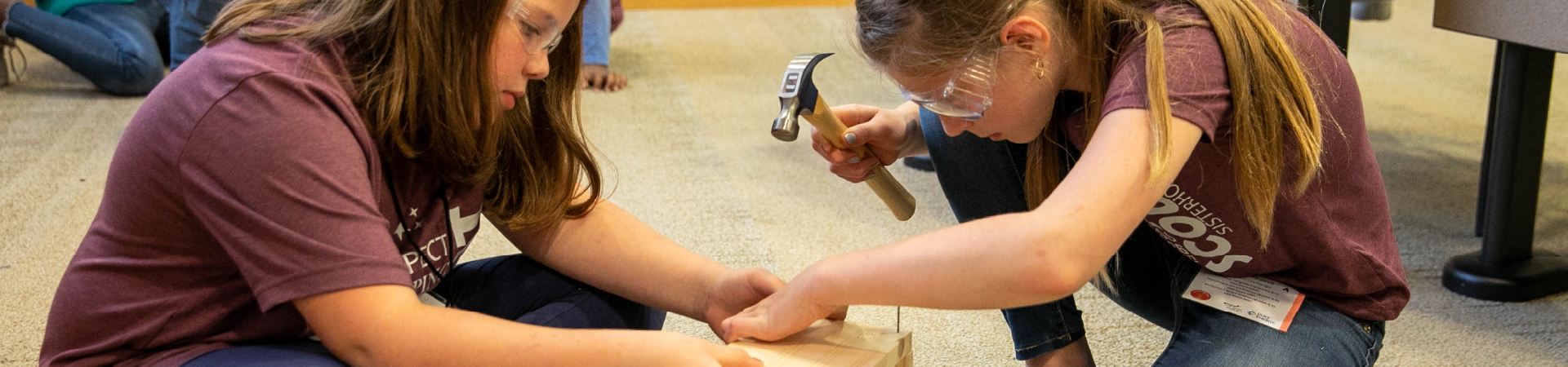  two Girl Scouts hammer on woodworking project 