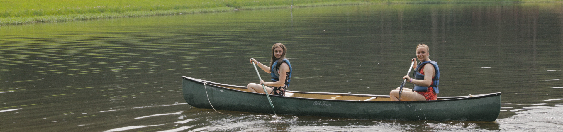  two girls kayaking across a lake 