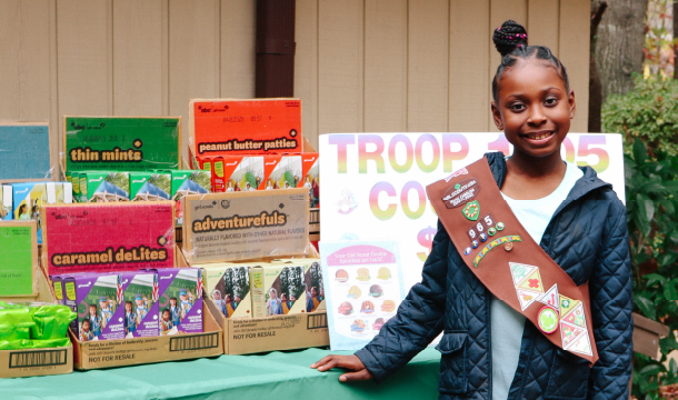Girl Scout Brownie stands near cookie booth