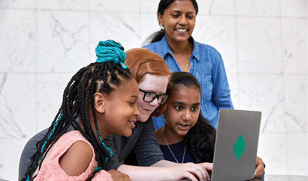 Girl Scouts crowd around a computer to work on a project