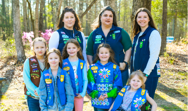 Troop leader with two Girl Scouts smiling outdoors