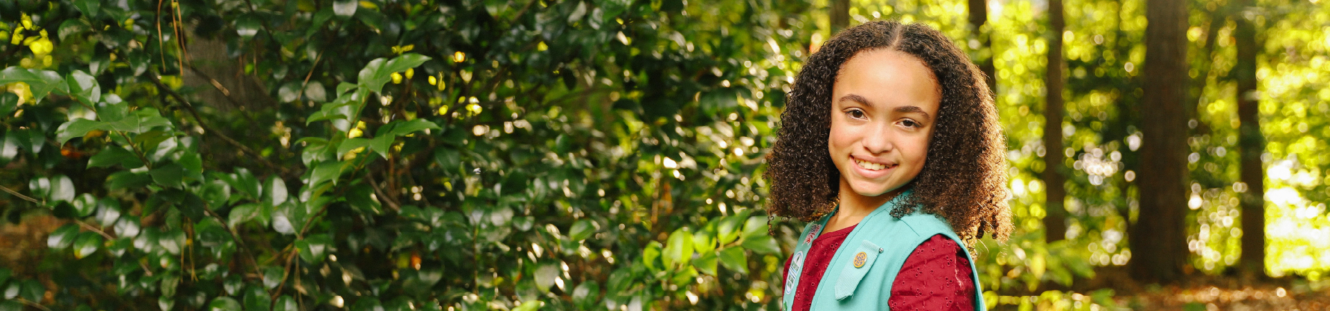  Girl Scout with red dress and Junior vest smiling in nature 